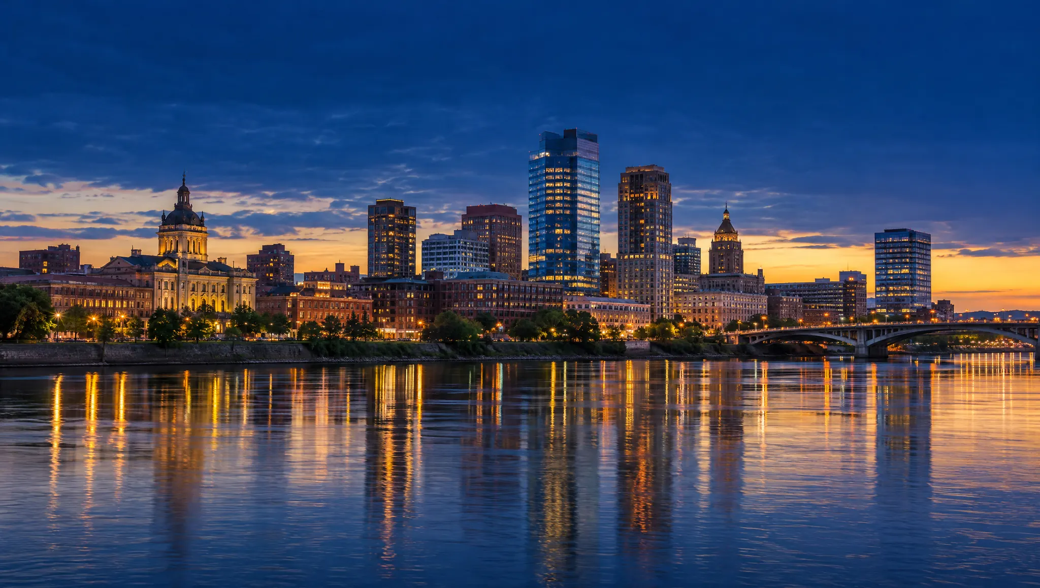 A city skyline reflected in a wide river at twilight